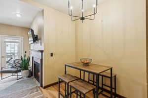 Dining room featuring light wood-type flooring, a lit fireplace, baseboards, and a chandelier