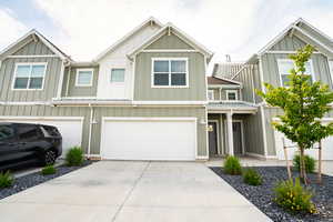 View of property with board and batten siding, driveway, a garage, and metal roof