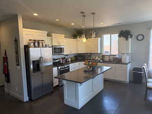 Kitchen featuring appliances with stainless steel finishes, dark countertops, backsplash, white cabinets, and recessed lighting
