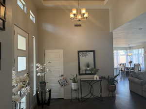 Foyer featuring a chandelier, a high ceiling, concrete flooring, and baseboards