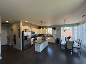 Kitchen with appliances with stainless steel finishes, dark countertops, baseboards, a textured ceiling, and white cabinets