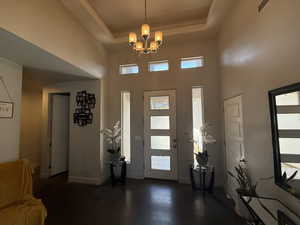 Foyer entrance featuring a chandelier, baseboards, a high ceiling, and a tray ceiling
