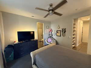 Bedroom with tile patterned flooring, a ceiling fan, and a spacious closet