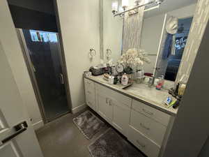 Bathroom featuring vanity, a shower stall, concrete flooring, and baseboards