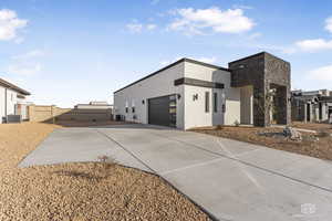 View of side of property with central air condition unit, an attached garage, driveway, and stucco siding