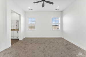 Primary bedroom featuring carpet floors, baseboards, ensuite bath, and a ceiling fan
