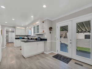 Kitchen featuring a peninsula, a sink, open shelves, white cabinets, and baseboards