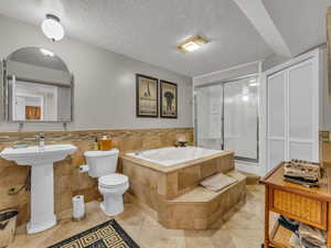 Bathroom featuring a garden tub, a stall shower, toilet, tile patterned floors, and a textured ceiling