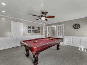 Rec room featuring a wainscoted wall, french doors, carpet, ceiling fan, and ornamental molding