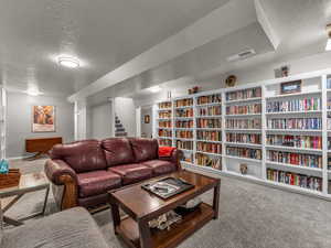 Living area with carpet, a textured ceiling, and stairs