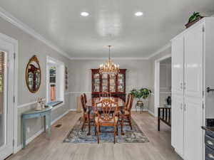 Dining area featuring a chandelier, ornamental molding, light wood finished floors, and baseboards