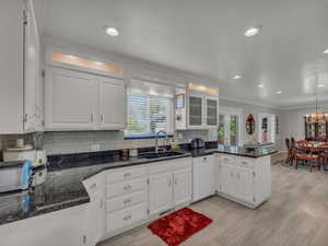 Kitchen with dishwasher, a sink, ornamental molding, a peninsula, and white cabinetry