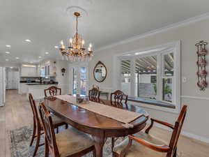 Dining space with french doors, a chandelier, light wood-type flooring, recessed lighting, and ornamental molding