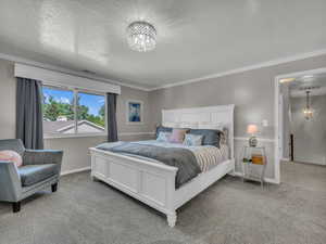 Carpeted bedroom featuring a chandelier, a textured ceiling, crown molding, and baseboards