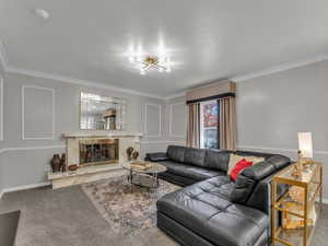Living room featuring ornamental molding, baseboards, a high end fireplace, and carpet floors