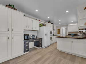 Kitchen featuring white appliances, open shelves, white cabinetry, decorative backsplash, and crown molding