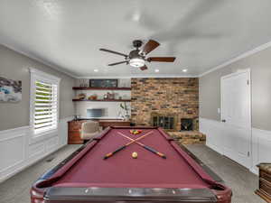 Game room with carpet flooring, billiards, a wainscoted wall, a ceiling fan, and crown molding
