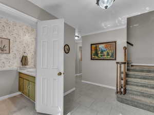 Bathroom featuring ornamental molding, vanity, tile patterned floors, and baseboards