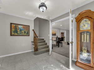 Entryway with ornamental molding, stairs, and baseboards