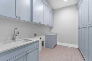 Washroom with electric dryer hookup, cabinet space, washer hookup, baseboards, and recessed lighting