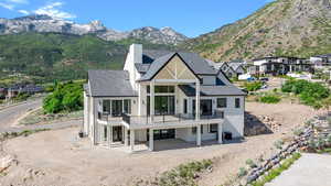 Back of property featuring a balcony, stucco siding, a chimney, roof with shingles, and a mountain view