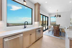 Kitchen with stainless steel dishwasher, a sink, recessed lighting, light wood-style floors, and pendant lighting