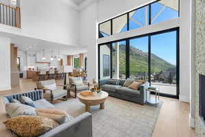 Living area with a mountain view, light wood-style flooring, healthy amount of natural light, a towering ceiling, and baseboards