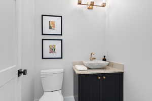 Half bath with toilet, vanity, and baseboards