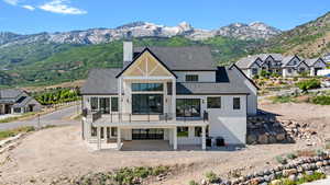 Rear view of house featuring a balcony, stucco siding, a chimney, and a mountain view