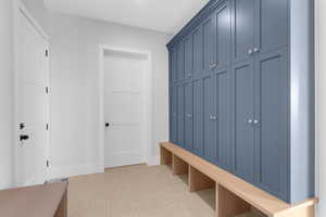 Mudroom featuring light colored carpet and baseboards