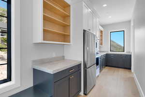 Kitchen featuring appliances with stainless steel finishes, open shelves, light countertops, white cabinetry, and light wood-style flooring