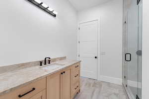 Full bathroom with vanity, a stall shower, and marble look tiles