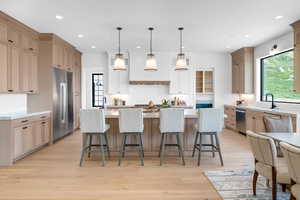 Kitchen featuring stainless steel appliances, custom range hood, decorative backsplash, recessed lighting, and light countertops