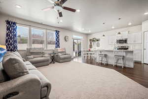 Living area with a textured ceiling, a ceiling fan, dark wood-style flooring, and recessed lighting