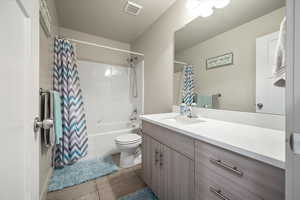 Main Bathroom featuring vanity, shower / bath combination with curtain, toilet, and tile patterned flooring