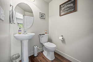 Half bath with wood finished floors, toilet, and baseboards