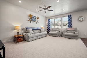Carpeted living area featuring a ceiling fan, baseboards, a textured ceiling, and recessed lighting
