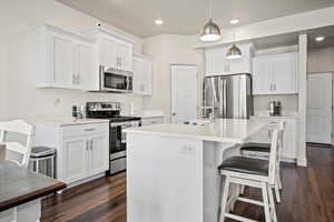 Kitchen featuring appliances with stainless steel finishes, dark wood-style flooring, light countertops, white cabinetry, and recessed lighting