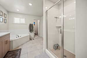 Full bath featuring vanity, a shower stall, a garden tub, toilet, and a textured ceiling