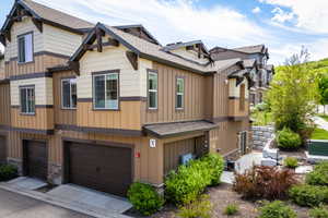 View of property featuring board and batten siding, roof with shingles, and an attached garage