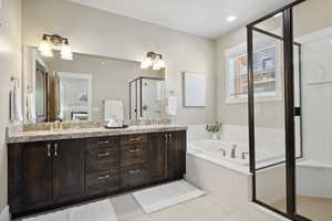 Full bathroom featuring a shower stall, a garden tub, double vanity, and tile patterned floors