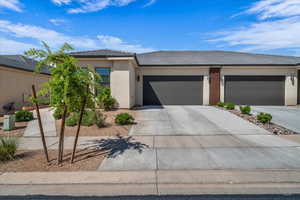 View of front of home featuring a tiled roof, an attached garage, driveway, and stucco siding