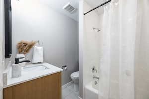 Full bath featuring toilet, vanity, tile patterned floors, shower / bath combo, and baseboards