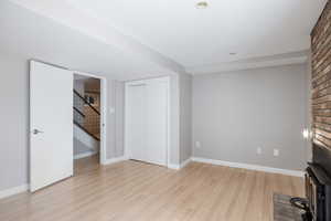 Unfurnished living room with light wood-style floors, stairway, and baseboards