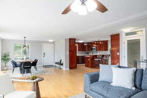 Living room featuring light wood finished floors, a ceiling fan, and baseboards