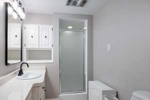 Bathroom featuring toilet, vanity, and a shower stall