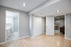 Unfurnished bedroom with light wood-type flooring, baseboards, a closet, connected bathroom, and recessed lighting