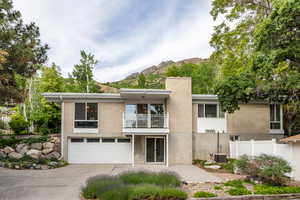 View of front of home featuring a balcony, driveway, brick siding, a garage, and a mountain view