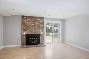 Unfurnished living room featuring wood finished floors, baseboards, a brick fireplace, and recessed lighting