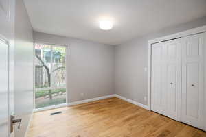 Unfurnished bedroom with light wood-type flooring, baseboards, access to exterior, and a closet